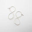 Load image into Gallery viewer, Pair of silver infinity-shaped earrings on a light gray background
